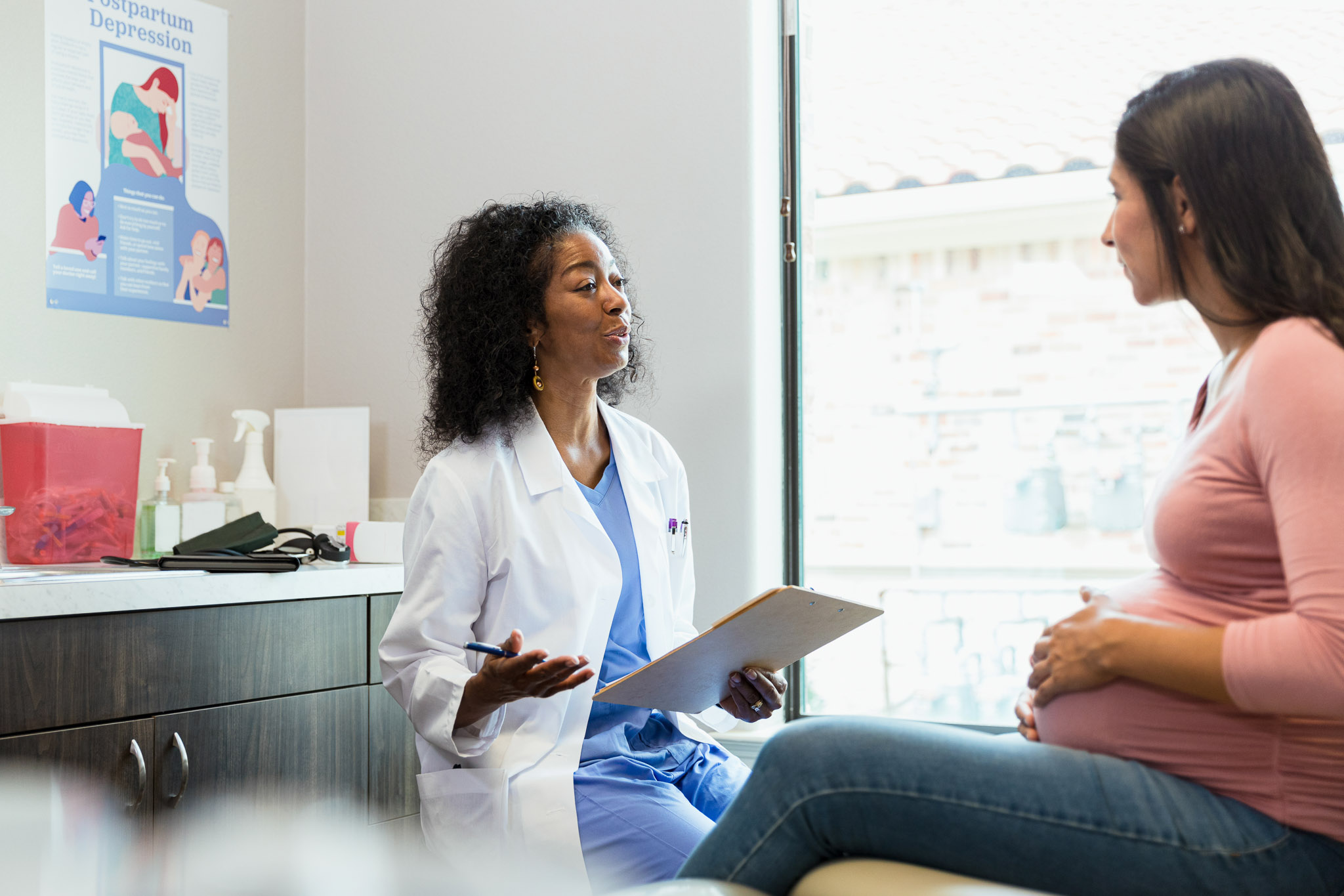 The mature adult doctor gestures as she gives advice to the mid adult pregnant woman.