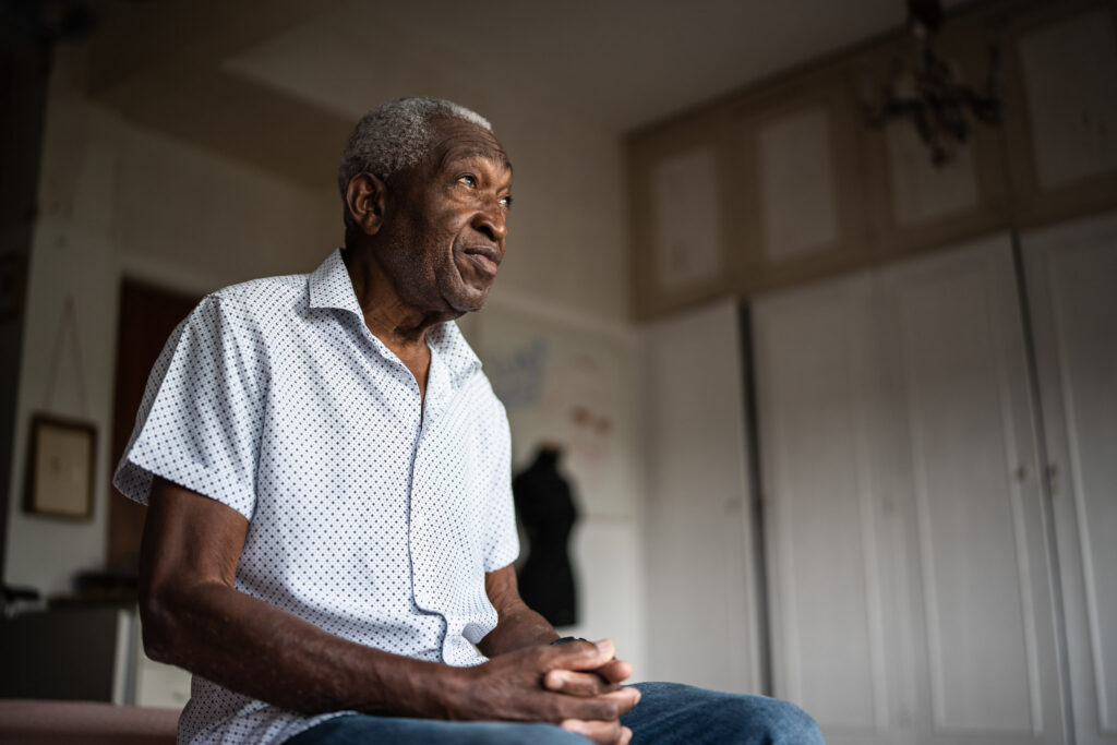 Senior man sitting on the bed and looking away
